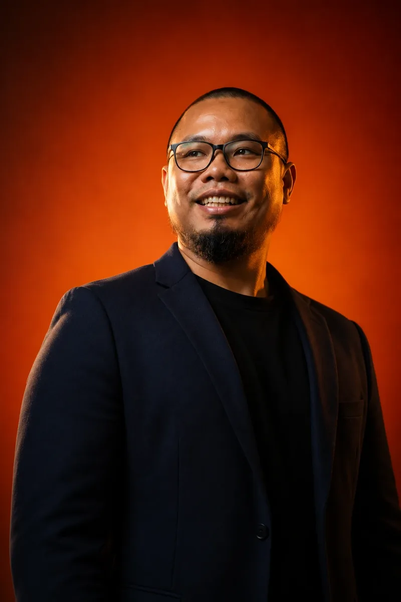 Hizami Radzi berkot gelap berlatarkan warna oren